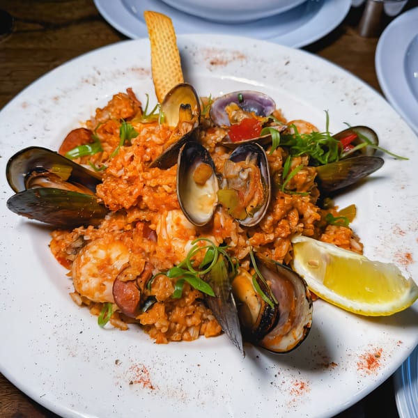 PK Oyster Bar's seafood paella with mussels, clams, shrimp, and chorizo, garnished with lemon and herbs.