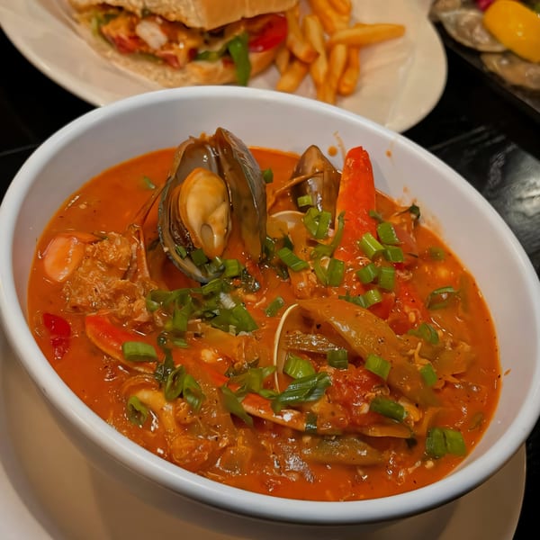 PK Oyster Bar's seafood gumbo with mussels, crab, and vegetables, topped with green onions.