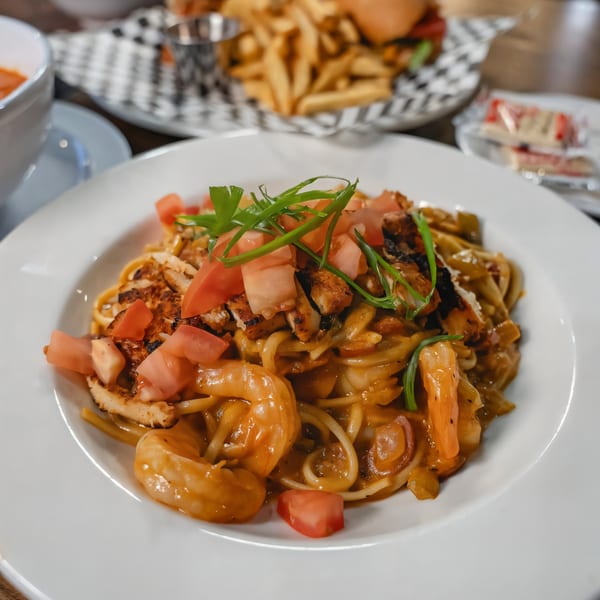 PK Oyster Bar's seafood pasta with shrimp, chicken, diced tomatoes, and green onions.